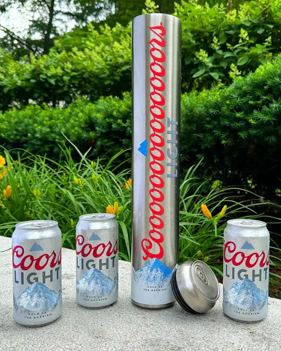 Comparaison physique de la canette Tallerboy 568 ml lancée par Coors Light le 15 juin 2026 face au tallboy classique 473 ml et à la canette standard 355 ml, trois canettes alignées de gauche à droite sur fond gris atelier, la Tallerboy se distingue par sa hauteur et son anneau argenté supérieur élargi, dispositif visuel qui révèle le saut de format