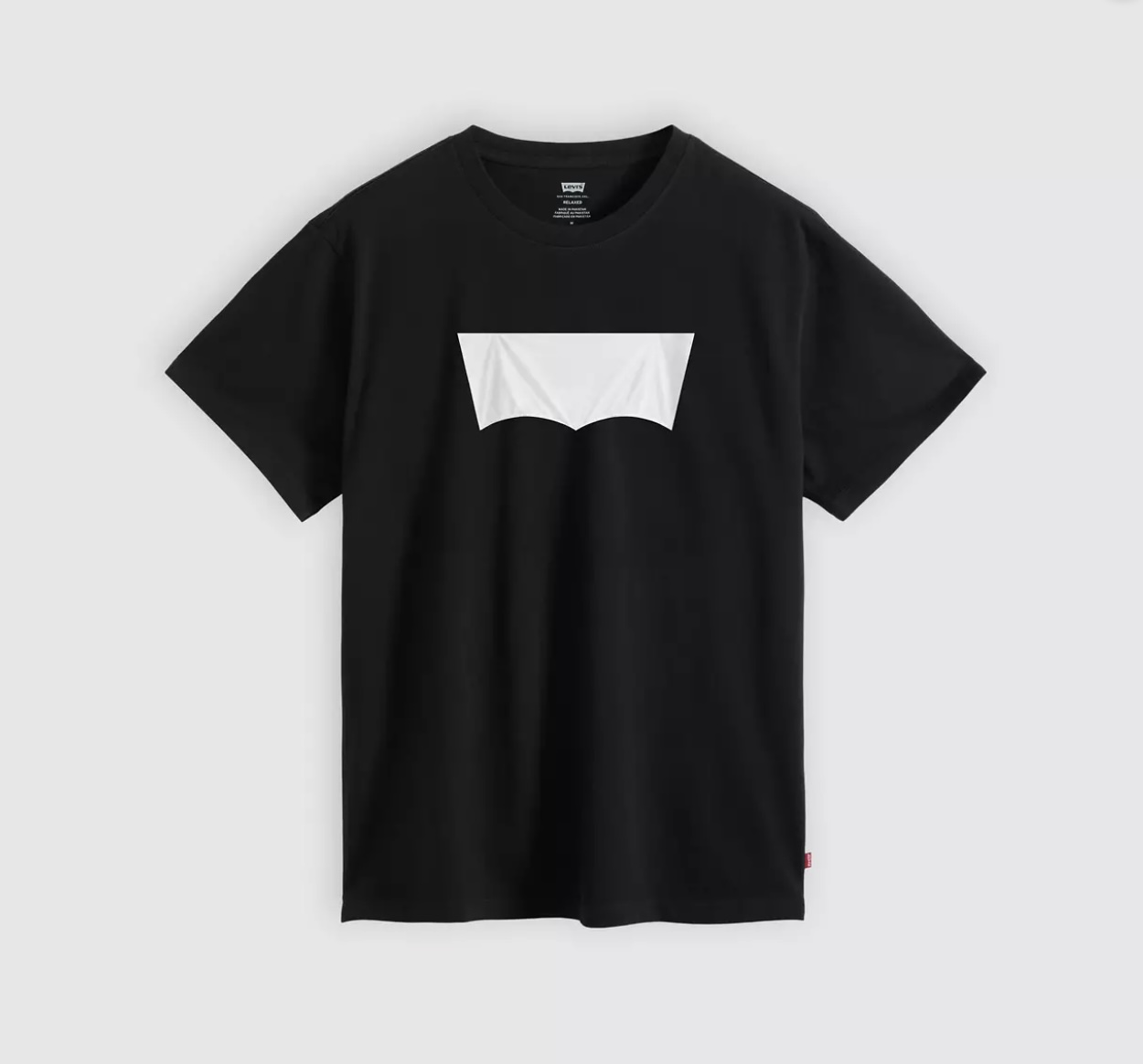 Photographie packshot studio à plat sur fond papier blanc uni du Nobody's Gonna Know Logo Tee de Levi's mis en vente le 2 juillet 2026, cadrage vertical serré sur un t-shirt noir en coton coupe droite manches courtes col rond suspendu comme flottant en apesanteur, sur la poitrine un large patch rectangulaire blanc légèrement froissé venant recouvrir l'ancien logo Batwing dont on devine encore la silhouette d'aile en relief, petite étiquette de composition tag Levi's Made in Pakistan Relaxed visible dans le col intérieur et petit label textile rouge Levi's cousu en bas à droite, ombre douce portée en bas, image de fiche produit e-commerce