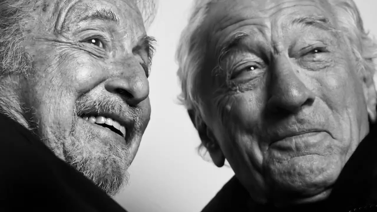 Photogramme de la campagne Warmer Together signée Wesayhi Sliema pour Moncler récompensée du Luxury Grand Prix aux Cannes Lions 2026, double portrait noir et blanc en très gros plan d'Al Pacino à gauche cheveux blancs barbe grise sourire éclatant levant les yeux vers Robert De Niro à droite cheveux blancs lissés vers l'arrière regard direct caméra expression émue, les deux acteurs habillés en doudounes Moncler noires, fond gris clair de studio, photographie signée Platon