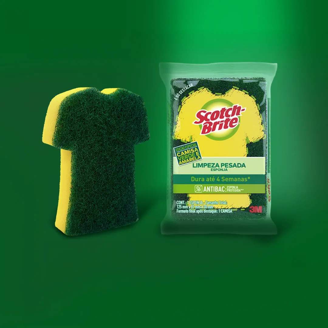 Édition limitée de l'éponge Limpeza Pesada signée Scotch-Brite habillée aux couleurs du maillot brésilien pour la Coupe du Monde 2026 dévoilée le 16 juin 2026, éponge double face vert jaune et bleu marine alignée dans son blister translucide, motif graphique inspiré du maillot Seleção, slogan en portugais Limpeza que dá jogo imprimé sur l'étiquette frontale